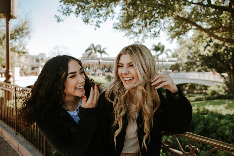 Duas amigas rindo juntas ao ar livre, celebrando a amizade