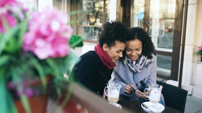 Amigas lendo uma carta juntas durante um café, um momento de gratidão compartilhada