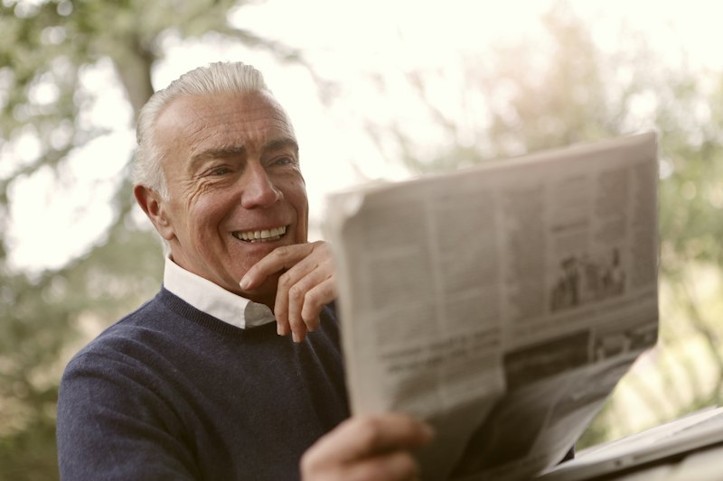 Idoso sorrindo ao receber uma carta de carinho do neto
