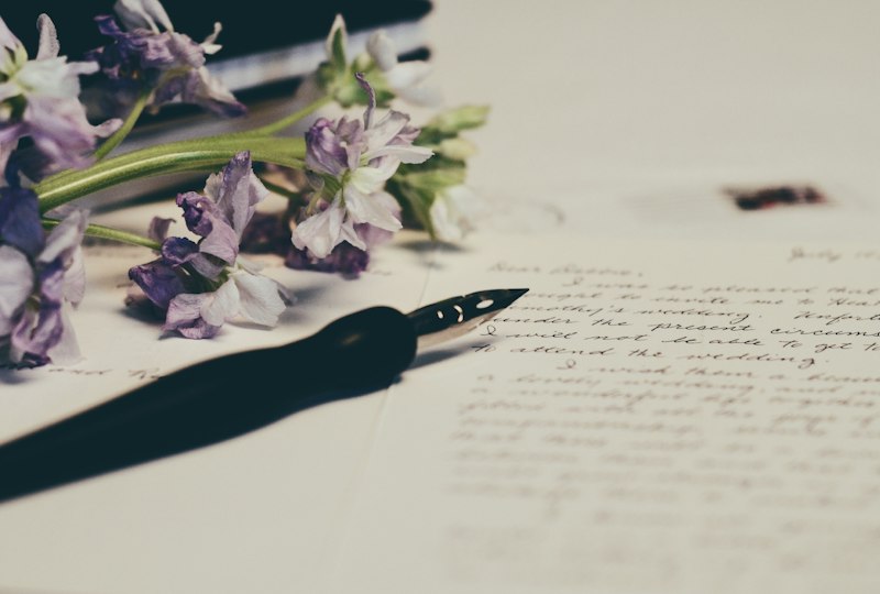 Carta para mãe que faleceu escrita à mão ao lado de flores e uma fotografia antiga