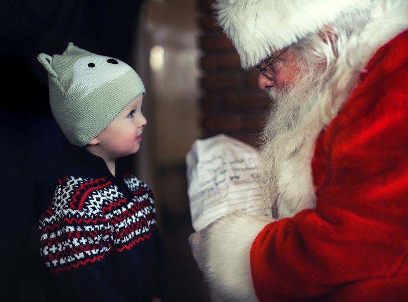 Criança escrevendo uma carta para o Papai Noel perto da árvore de Natal