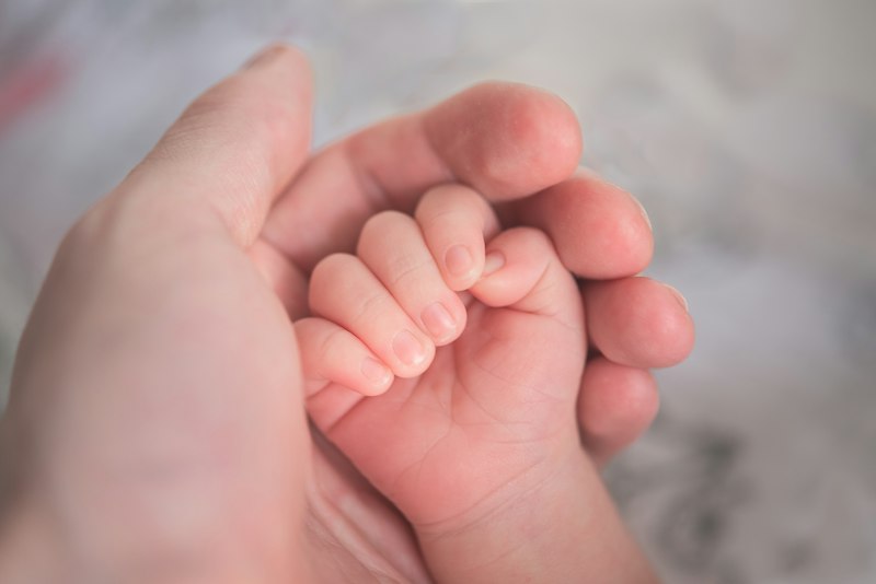 Mãos de pai ou mãe segurando as mãos de um bebê, simbolizando o amor registrado em uma carta para o filho