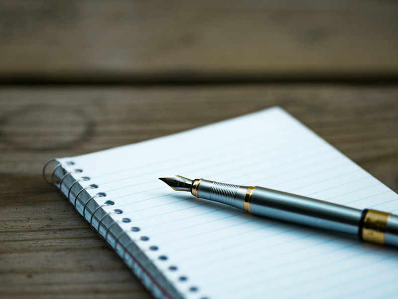 Caderno de journaling aberto com caneta sobre uma mesa de madeira