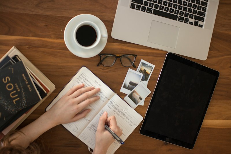 Pessoa escrevendo em um caderno de journaling com uma xícara de café pela manhã