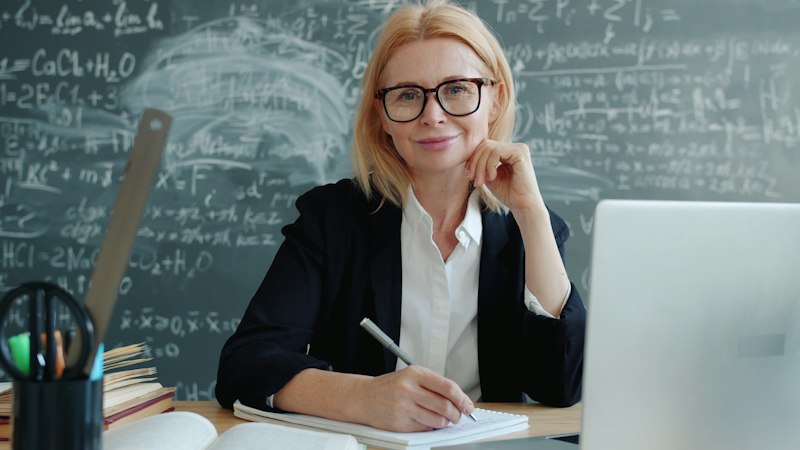 Professor escrevendo à mão uma mensagem de despedida para alunos em sua mesa