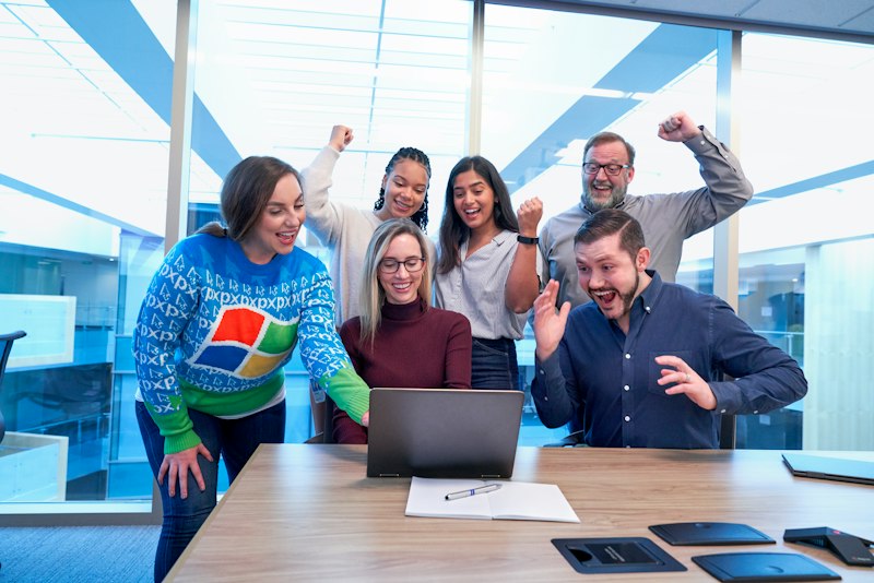 Equipe celebrando junta no escritório ao receber uma mensagem de fim de ano para equipe