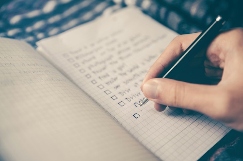 Pessoa escrevendo metas e objetivos em um caderno, representando o planejamento para 2027