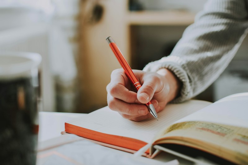 Pessoa escrevendo metas de vida à mão num caderno, em forma de carta para o futuro