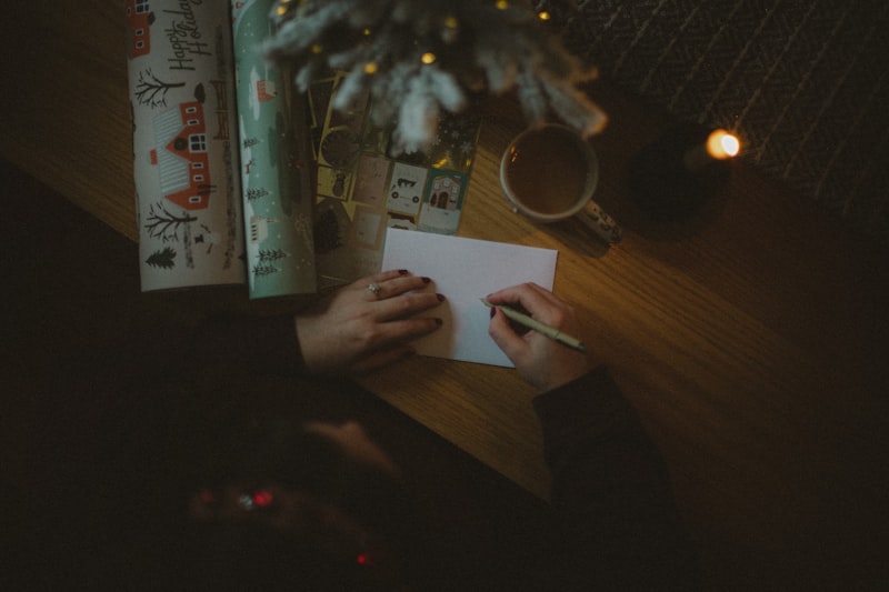 Pessoa escrevendo uma carta especial à luz de pisca-piscas de Natal